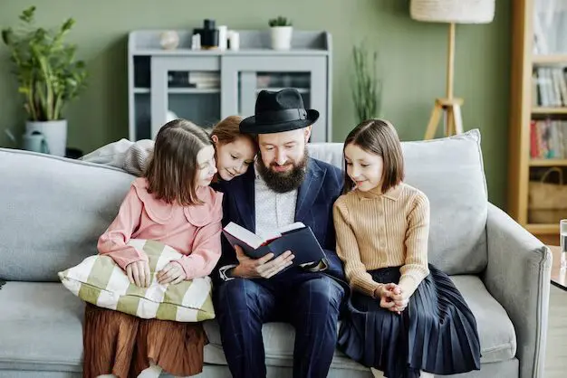 A man sitting on the couch with two girls.